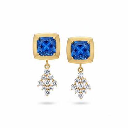 Gold earrings with blue gemstones and diamond-like elements on a white background