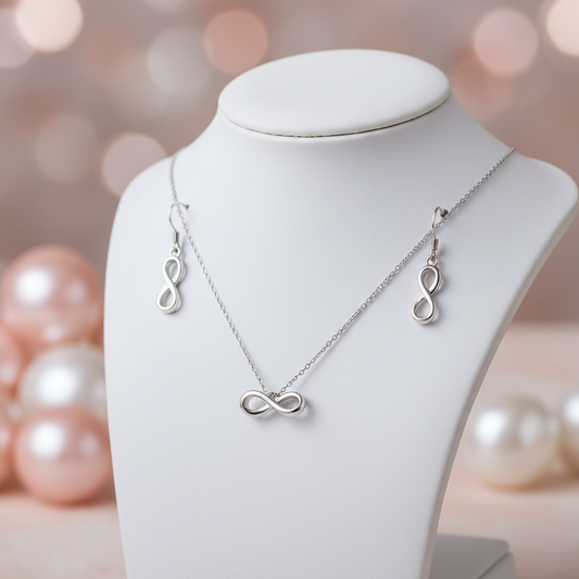 Silver infinity necklace and earrings on a mannequin bust with blurred pearls in the background