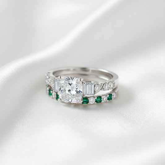 Silver ring with a large central gemstone and smaller emerald stones on a white background